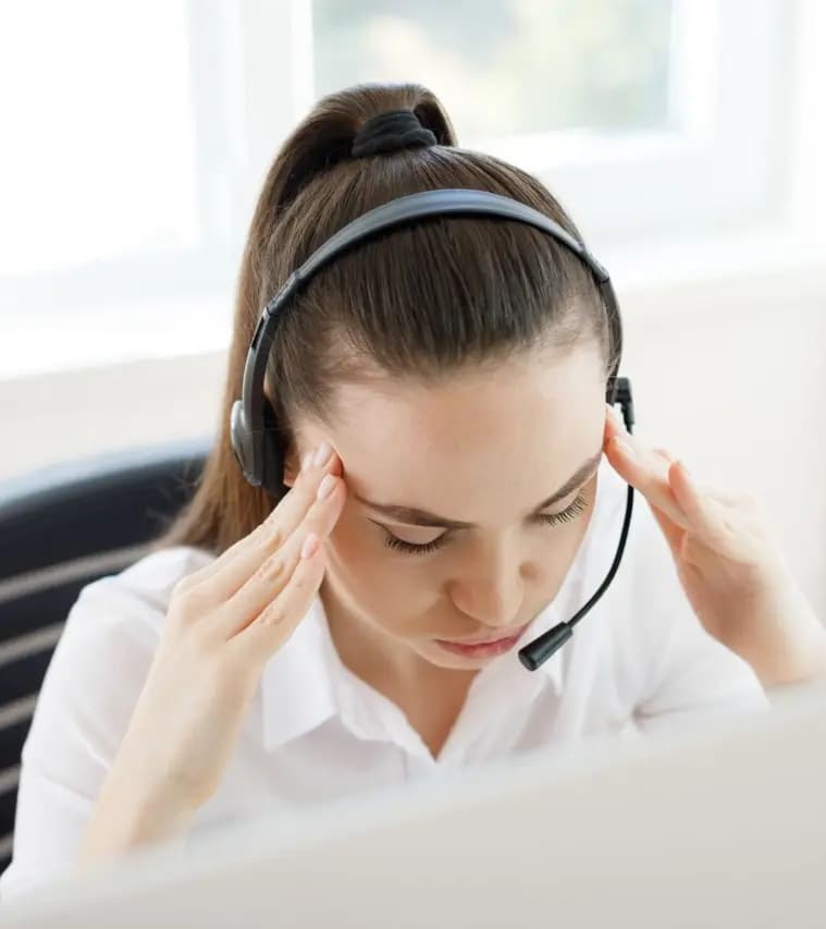 Atendente de call center com as mãos na cabeça, sobrecarregada